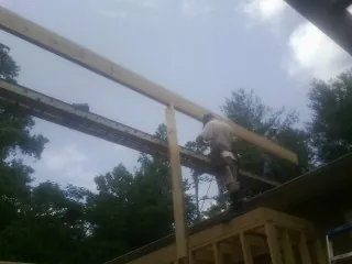 Carpenter setting a ridge beam over a new addition frame — Ice Dam Removal by Roofing Brothers in Brownell