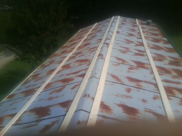 Rusted metal roof panels with new wood purlins before replacement — Storm Damage Roof Repair in Brownell by Roofing Brothers