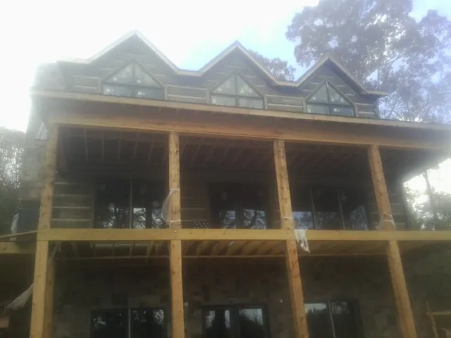 Dormers and porch framing on a large log home under construction — Roof Coating work by our crew in Brownell