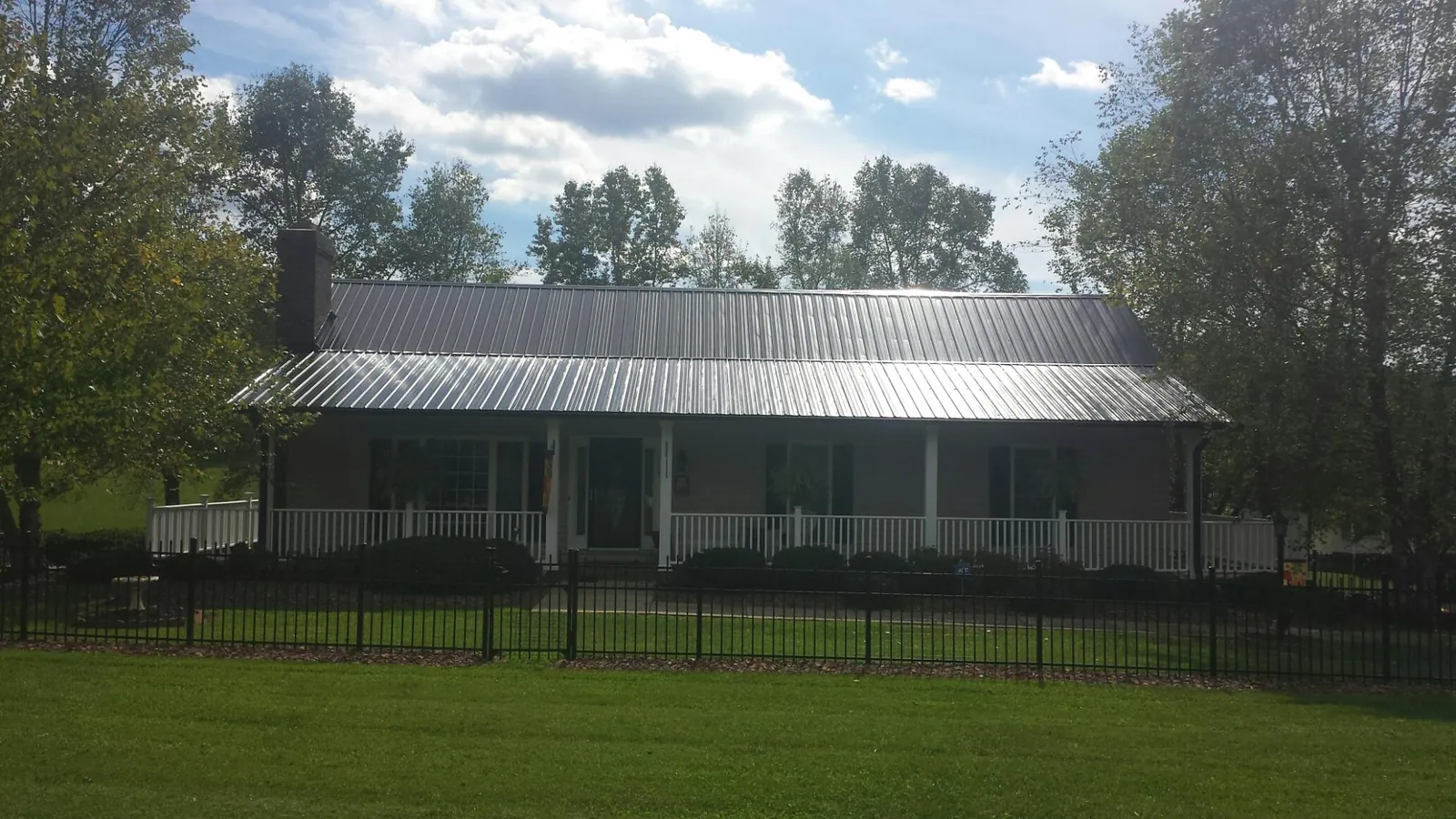 Gray metal roof on a brick ranch with a full width front porch — Gutter Guard Installation work by our crew in Brownell