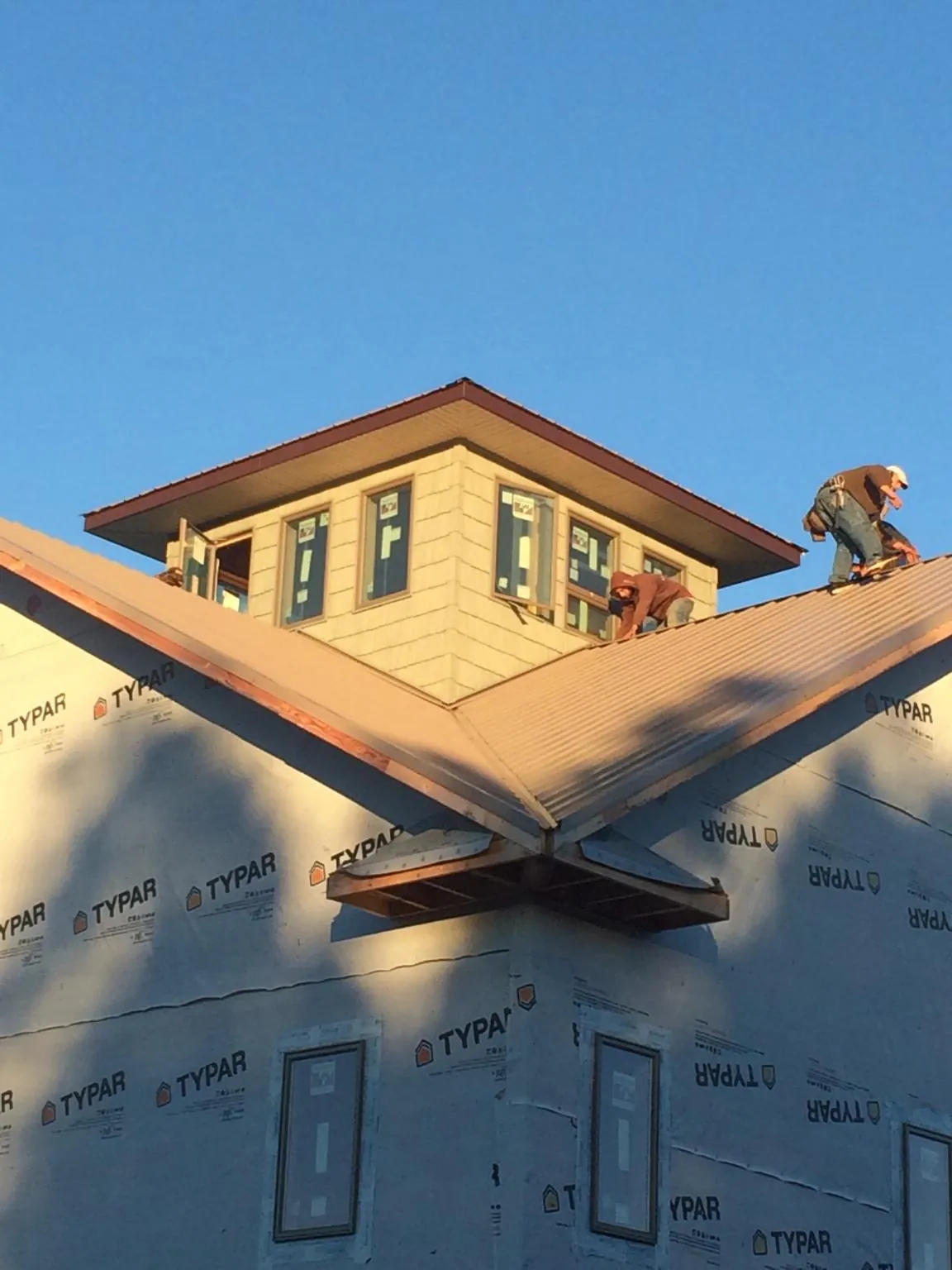 Roofers working around a rooftop cupola on a new metal roof at sunset — Roof Waterproofing in Brownell by Roofing Brothers